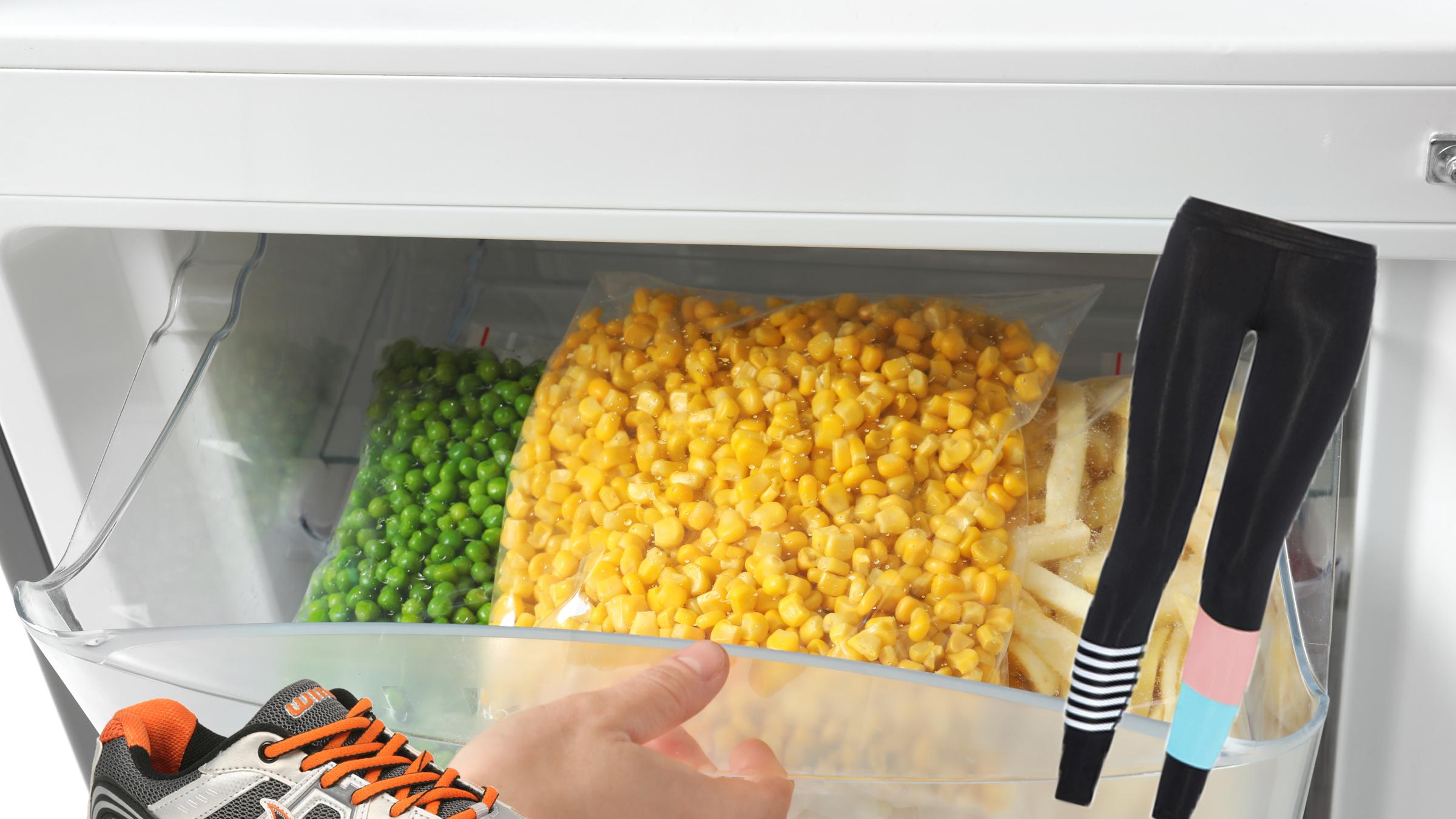 Woman opening refrigerator drawer with frozen vegetables, closeu